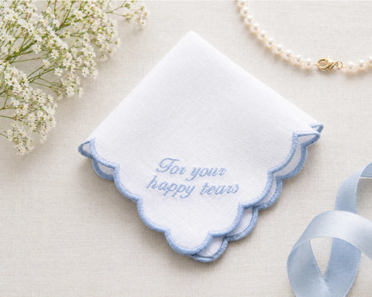 Embroidered handkerchief with 'For your happy tears' text on a light background with flowers and ribbon.