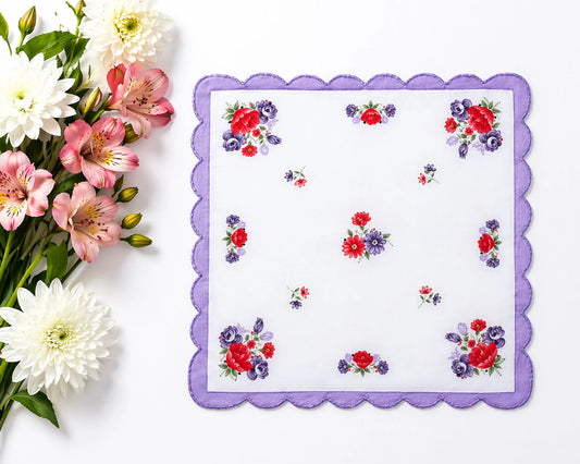 Floral-patterned handkerchief with a purple border on a white background, accompanied by a bouquet of flowers.