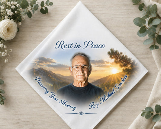 Memorial card with a photo of an elderly man and 'Rest in Peace' text, surrounded by flowers on a wooden surface.