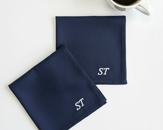 Four white cotton handkerchiefs for men showing different navy and black embroidered block monograms