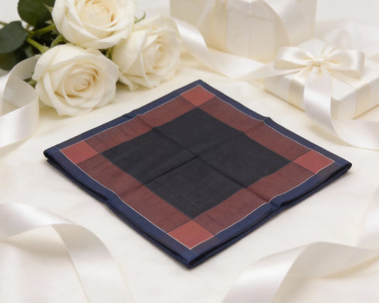 Navy and red checkered pocket square on a white fabric background with white roses.