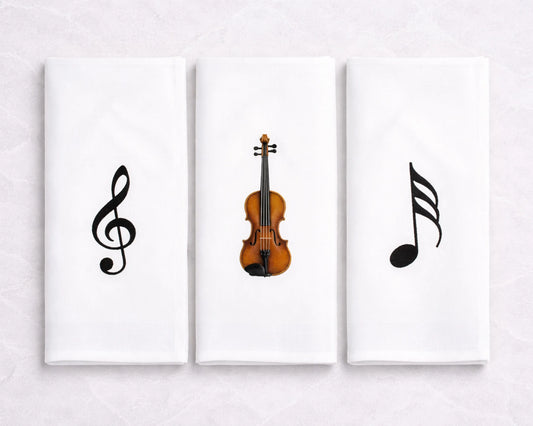 Three hanky artworks featuring musical symbols and a violin on a white wall.
