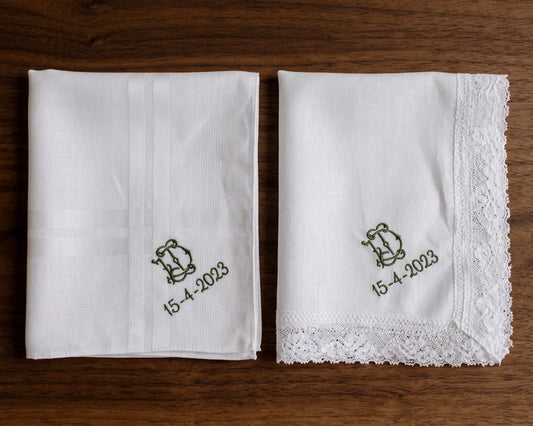 Two white handkerchiefs with embroidered designs and dates on a wooden surface