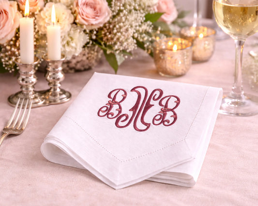 White napkin with red monogram on a table setting with candles and flowers