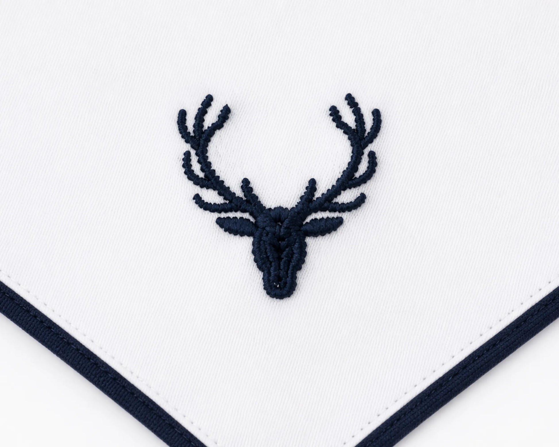 Embroidered deer head design on a white fabric with navy border