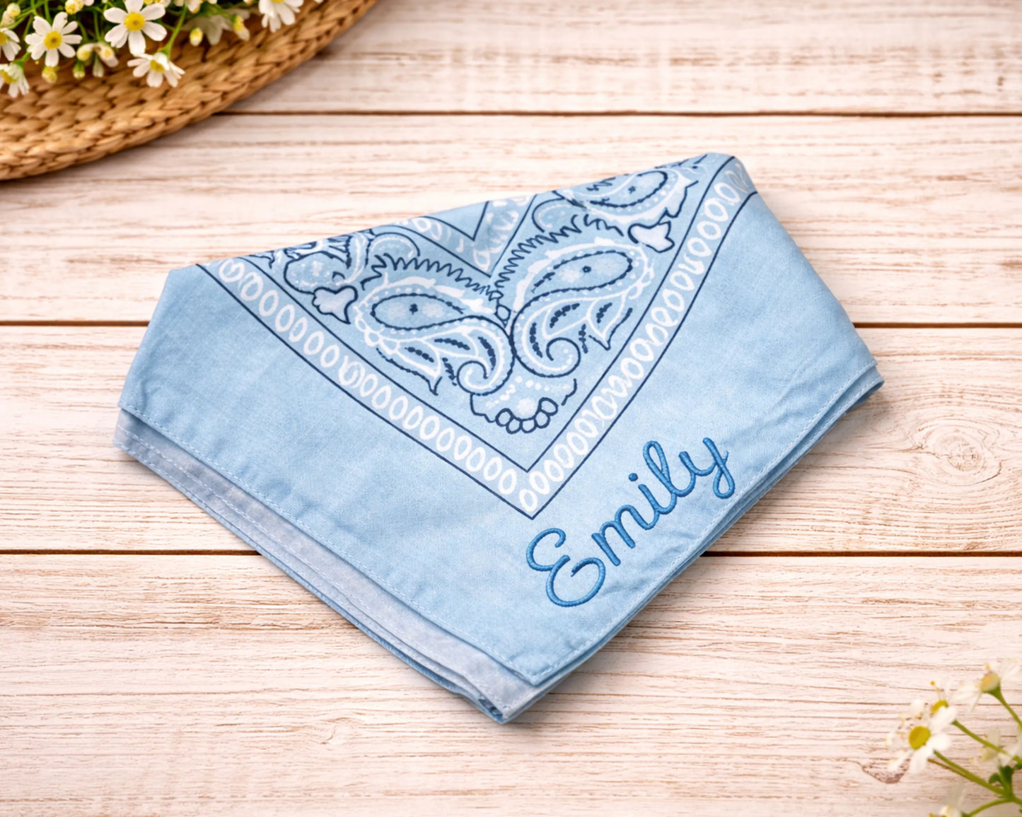 Blue bandana with white paisley pattern and 'Emily' embroidery on a wooden surface.