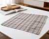 Plaid fabric on a white surface with a candle and book in the background
