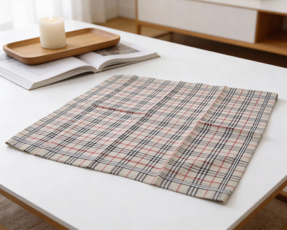 Plaid fabric on a white surface with a candle and book in the background