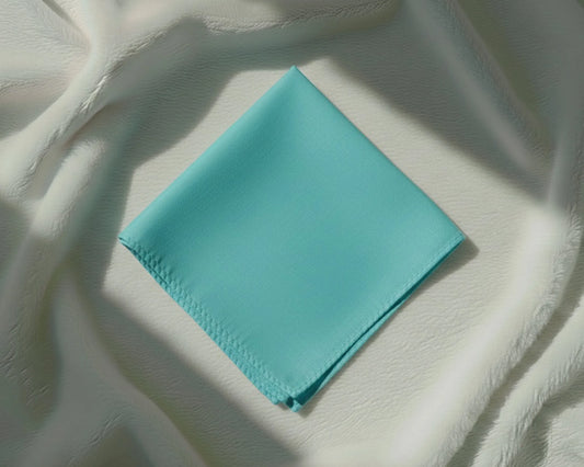 Turquoise fabric square on a textured white background