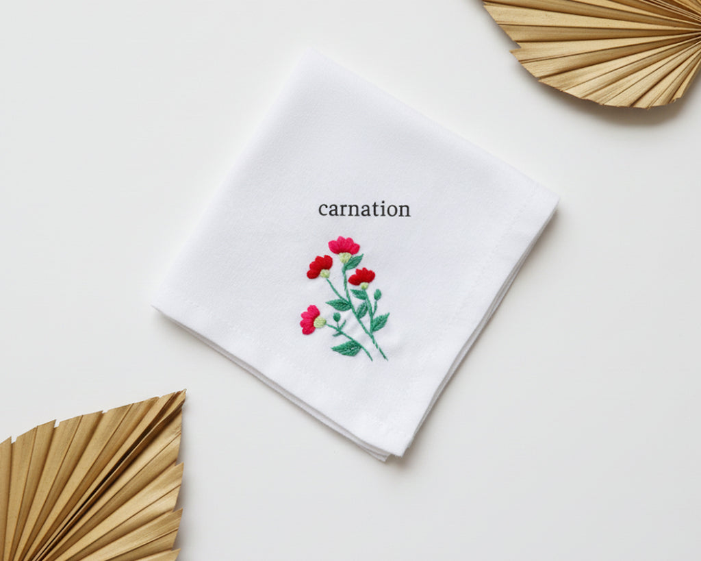 Pure white cotton handkerchief featuring a centered red carnation embroidery with green stems on a neutral background
