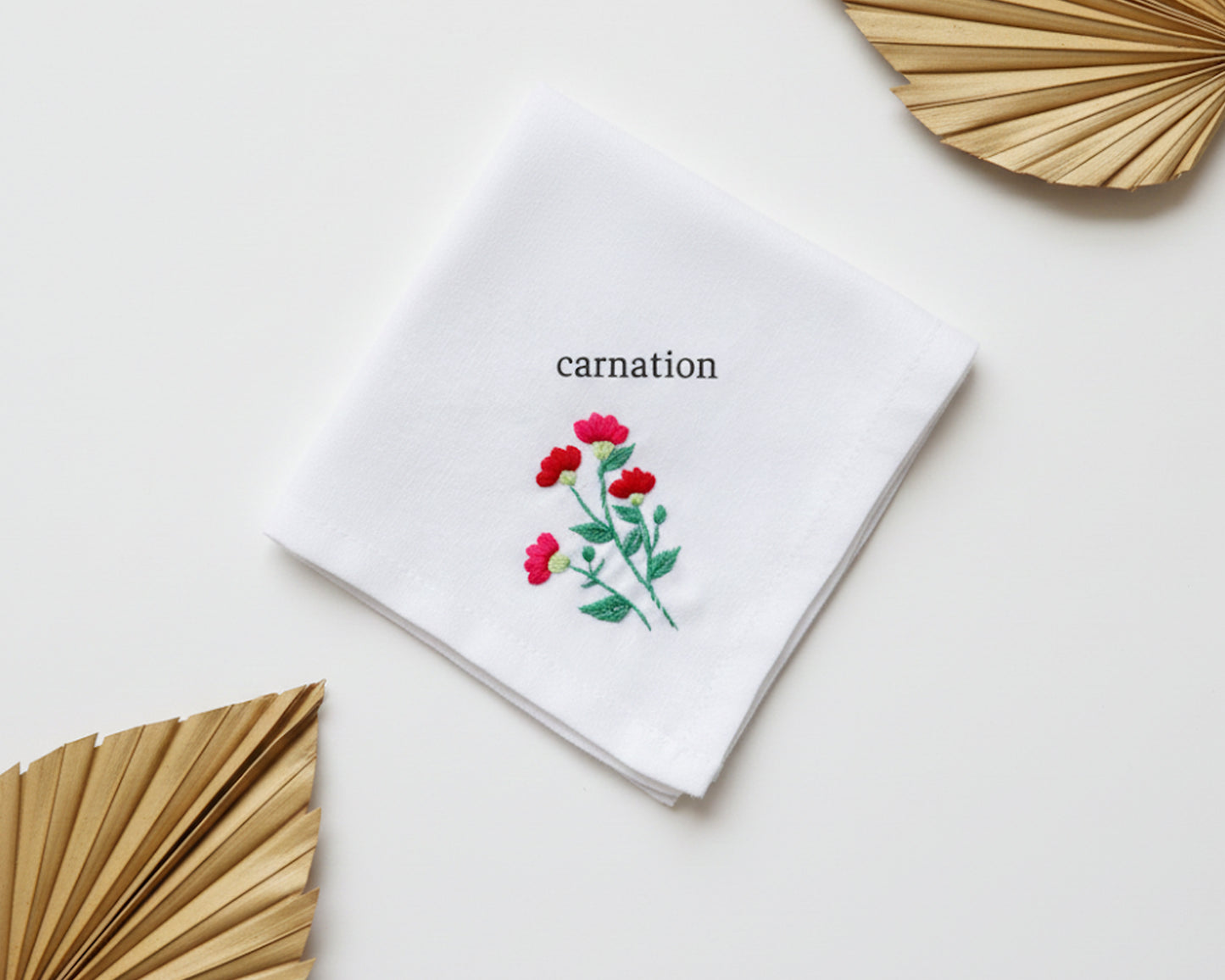 Pure white cotton handkerchief featuring a centered red carnation embroidery with green stems on a neutral background