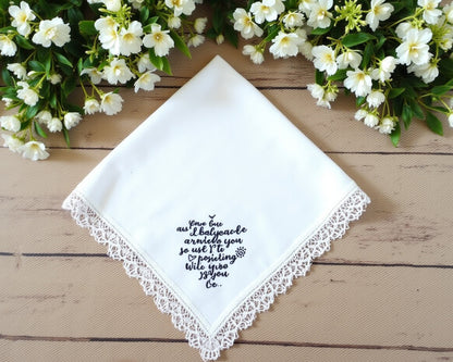 Personalized white cotton wedding handkerchief featuring detailed floral lace edging and a custom 2023 date on a white brick background