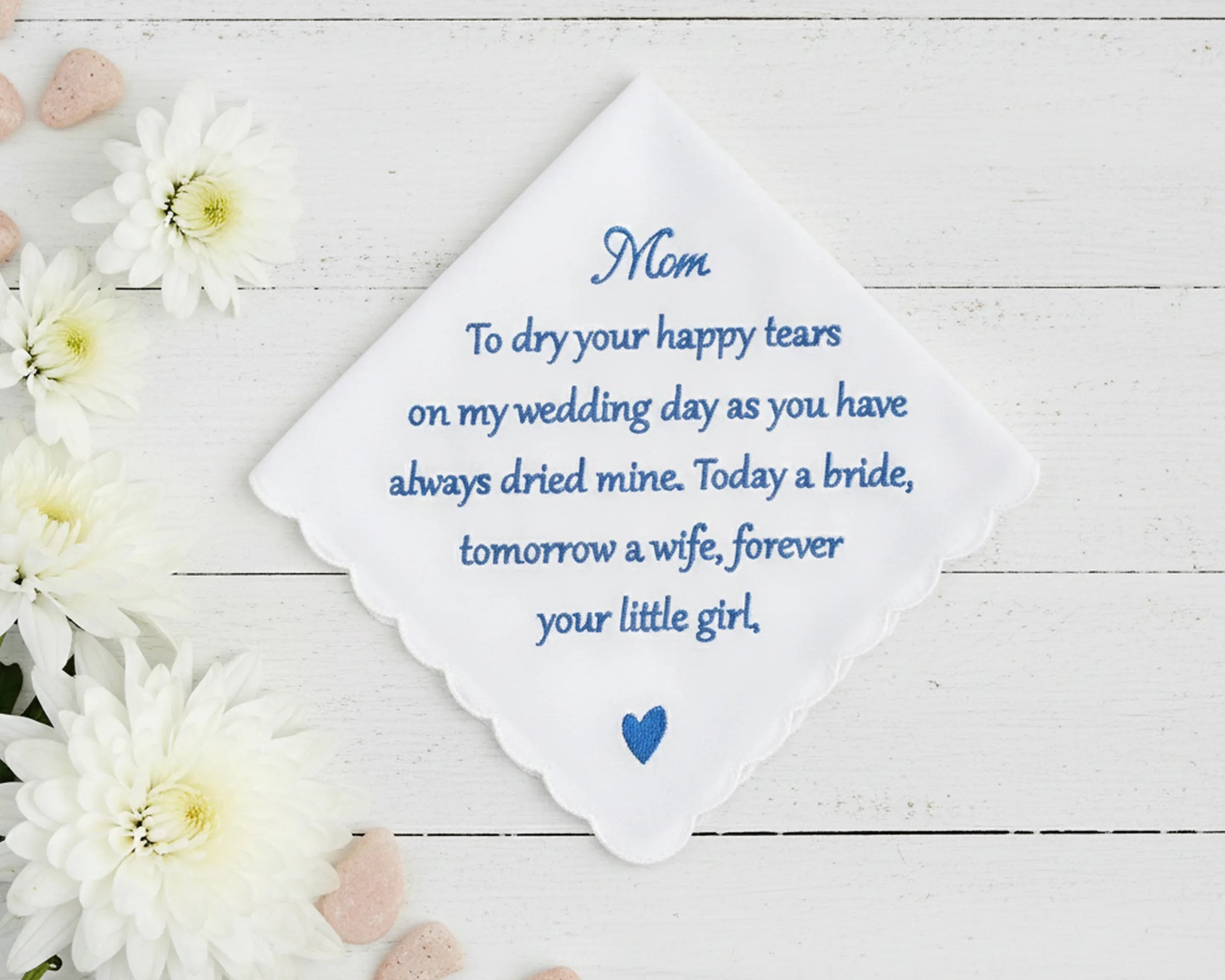 Handkerchief with embroidered message on a wooden surface with flowers