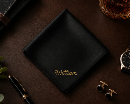Black cotton hanky with 'William' embroidery on a dark surface with accessories.