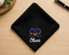 Black handkerchief with printed  design and 'Oliver' text on a wooden surface