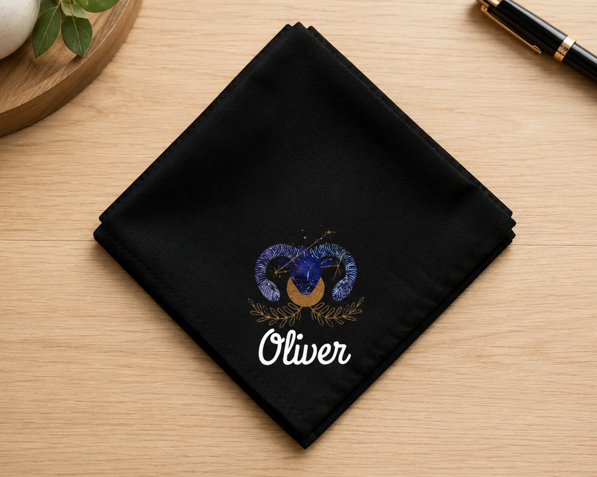 Black handkerchief with printed  design and 'Oliver' text on a wooden surface