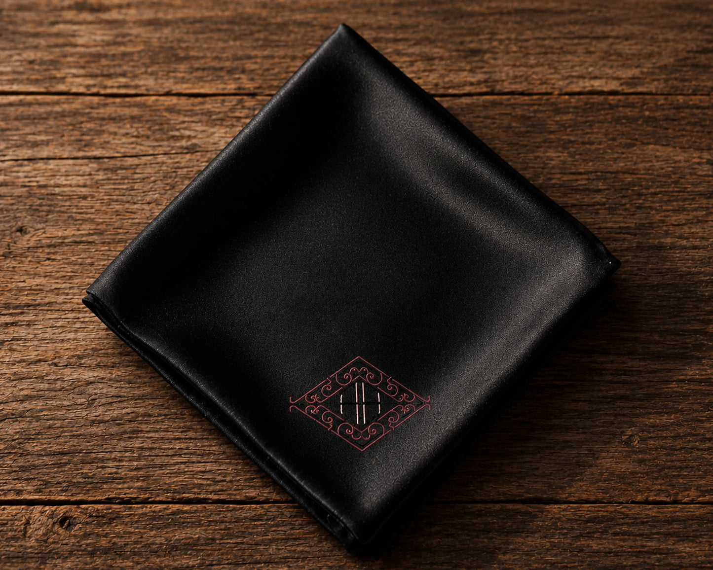 Black satin hanky with a monogram on a wooden surface