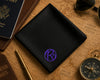 Black wallet with a purple logo on a vintage world map with travel items.