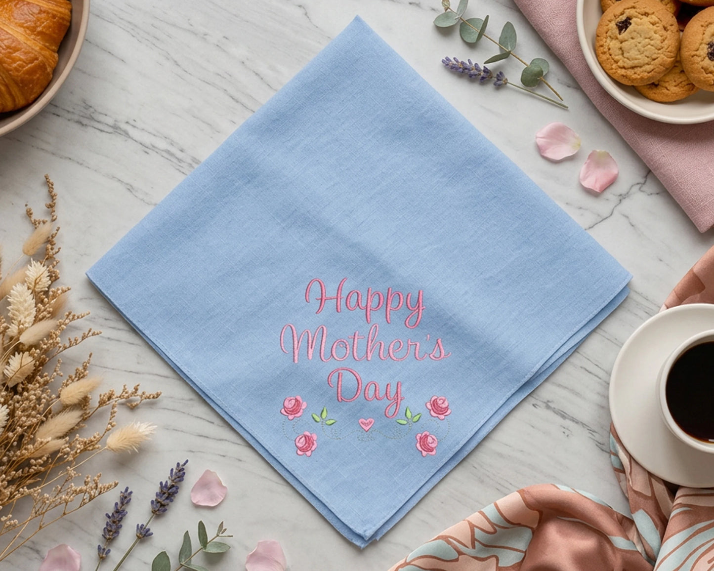 Blue hankie with 'Happy Mother's Day' text on a table with coffee, cookies, and flowers.