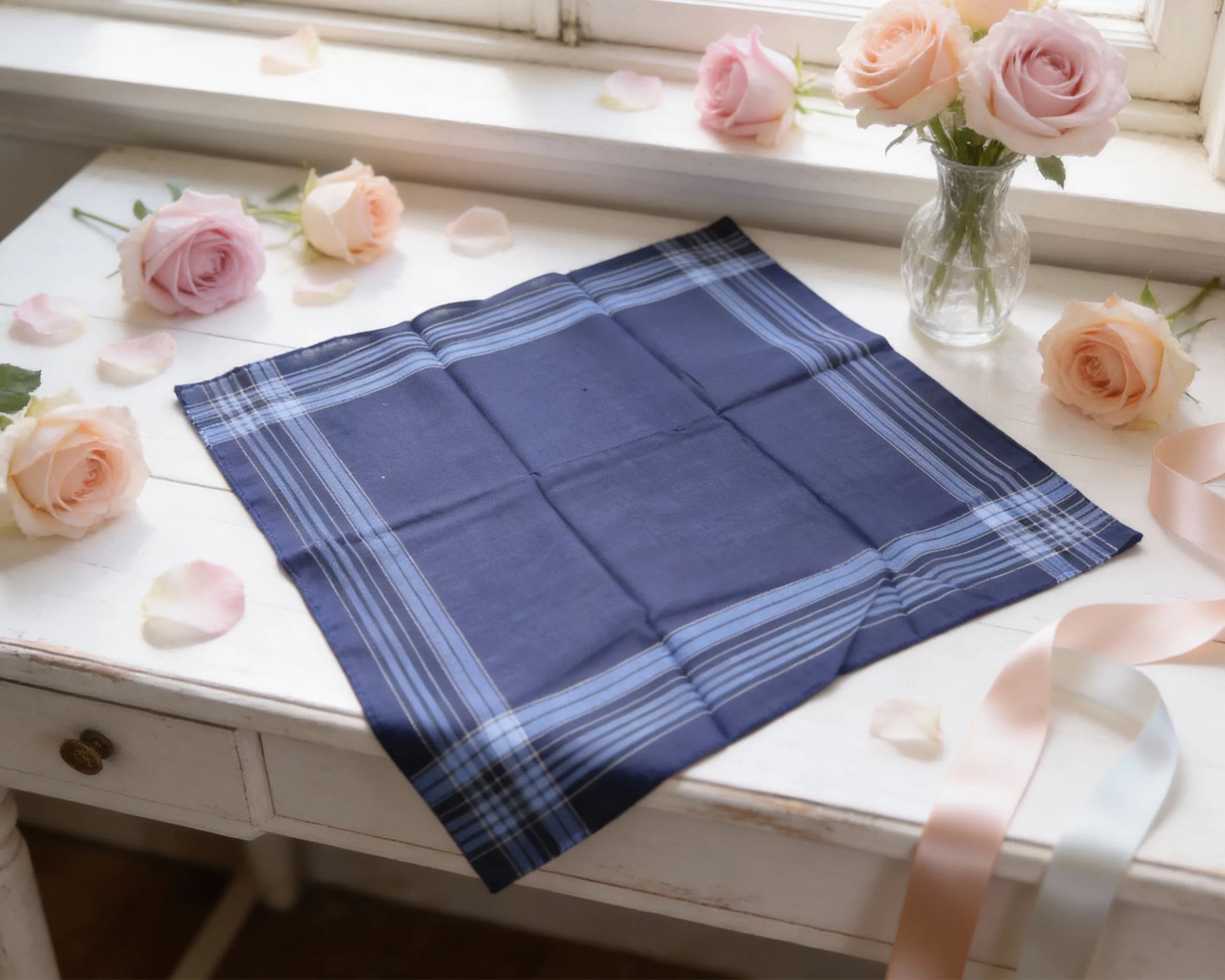Blue plaid fabric on a white surface with pink flowers and ribbons.