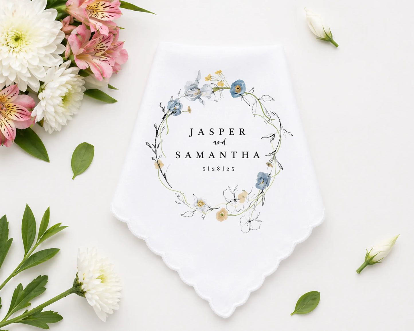 Checkered handkerchief with pink border on a white surface with flowers and leaves.