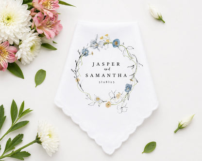 Checkered handkerchief with pink border on a white surface with flowers and leaves.