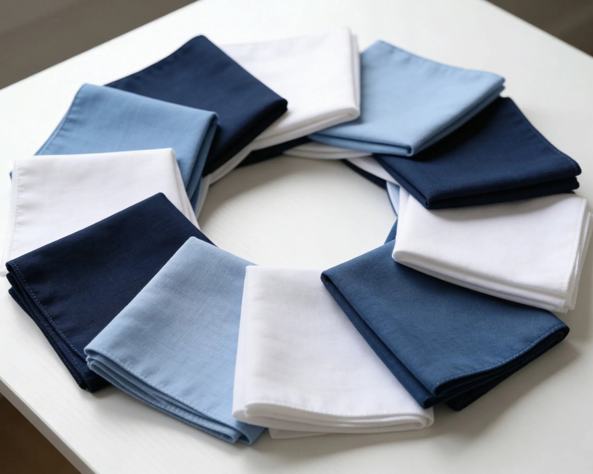 Circular arrangement of folded blue, white, and navy hanky on a white surface.