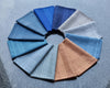 Circular arrangement of folded hanky  in various blue tones on a textured gray background