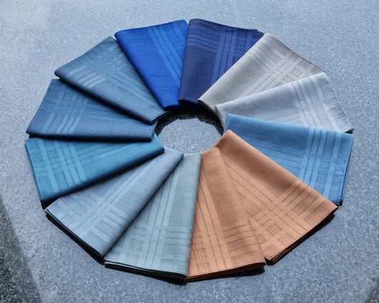Circular arrangement of folded hanky  in various blue tones on a textured gray background