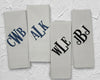 Four folded white cotton handkerchiefs showing diverse navy blue and black monogrammed initial embroidery