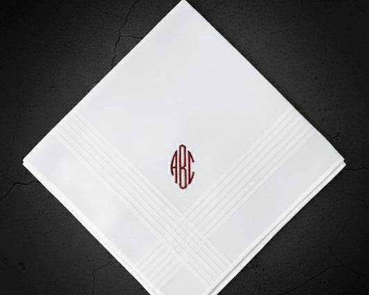 White cotton men's handkerchief with a bold red CME block initial monogram next to a coffee cup