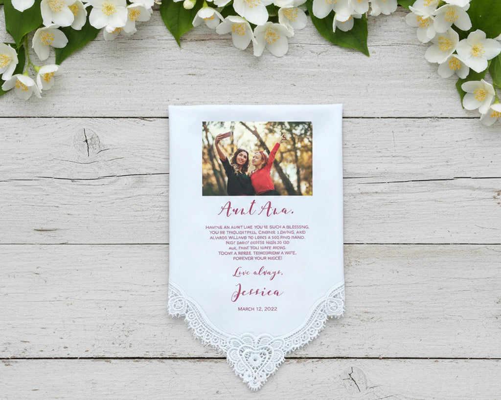 Lace Handkerchief with custom message surrounded by pink flowers on a light wooden surface