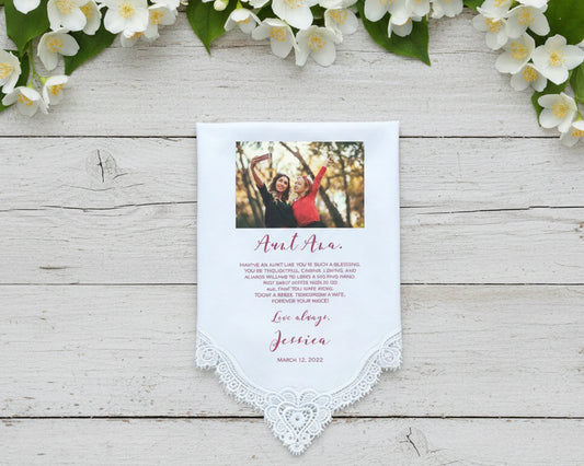 Lace Handkerchief with custom message surrounded by pink flowers on a light wooden surface