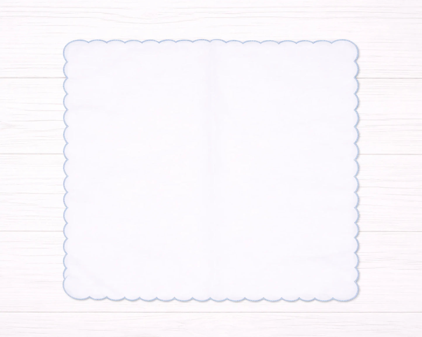 Decorative white scalloped edge hanky border on a light wooden background