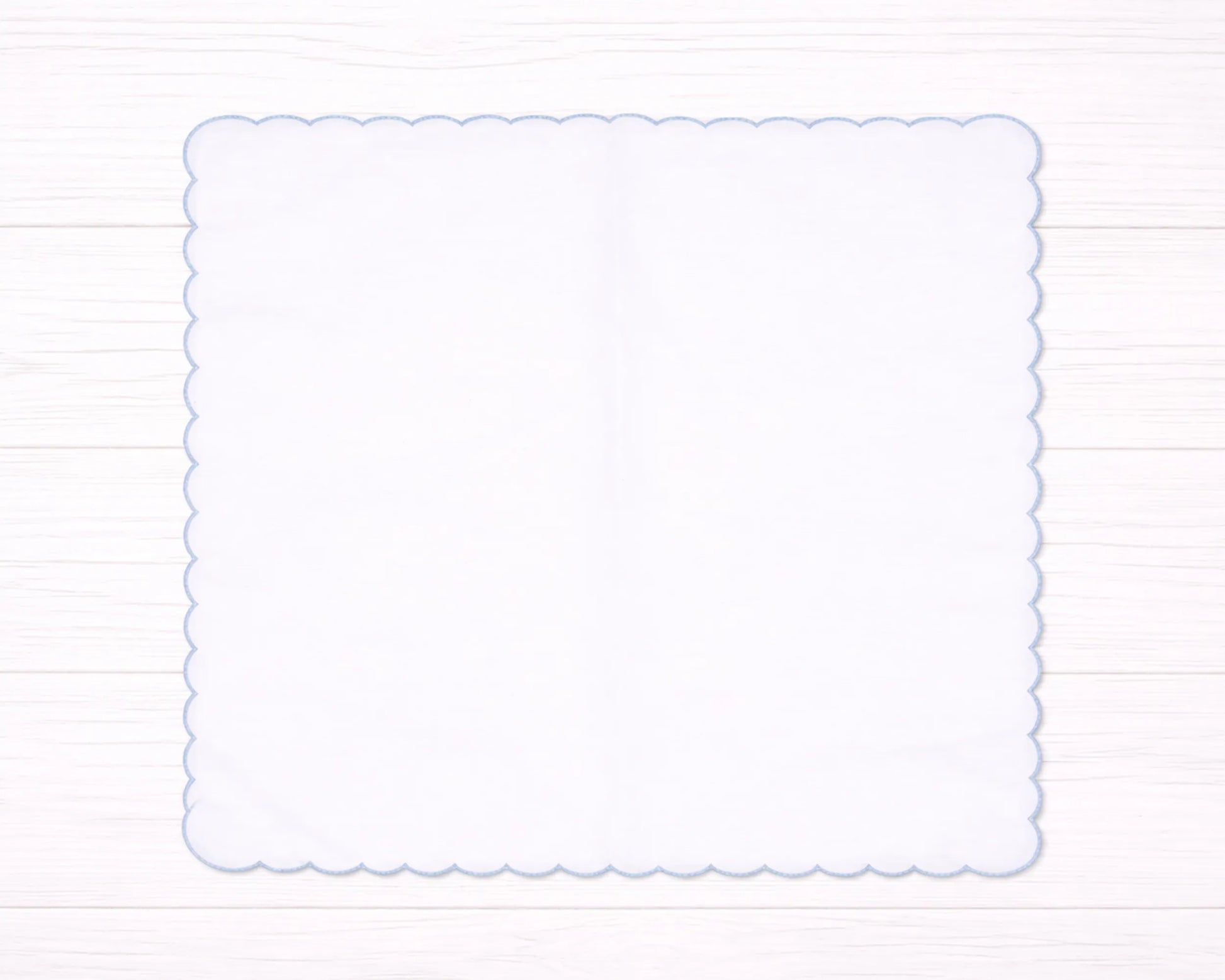 Decorative white scalloped edge hanky border on a light wooden background