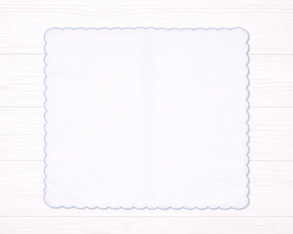 Decorative white scalloped edge hanky border on a light wooden background