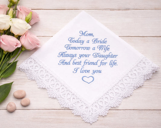 Embroidered handkerchief with a message on a wooden surface with flowers and stones.