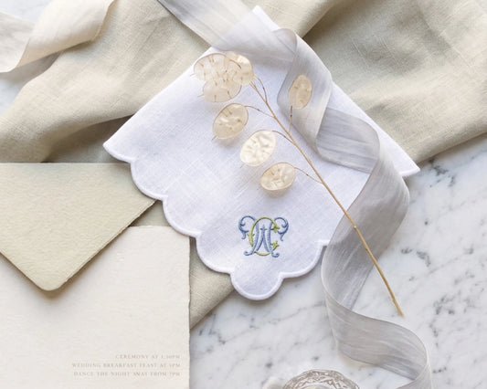Embroidered handkerchief with floral design and monogram on marble surface
