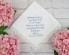 Handkerchief with embroidered message surrounded by pink flowers on a light wooden surface