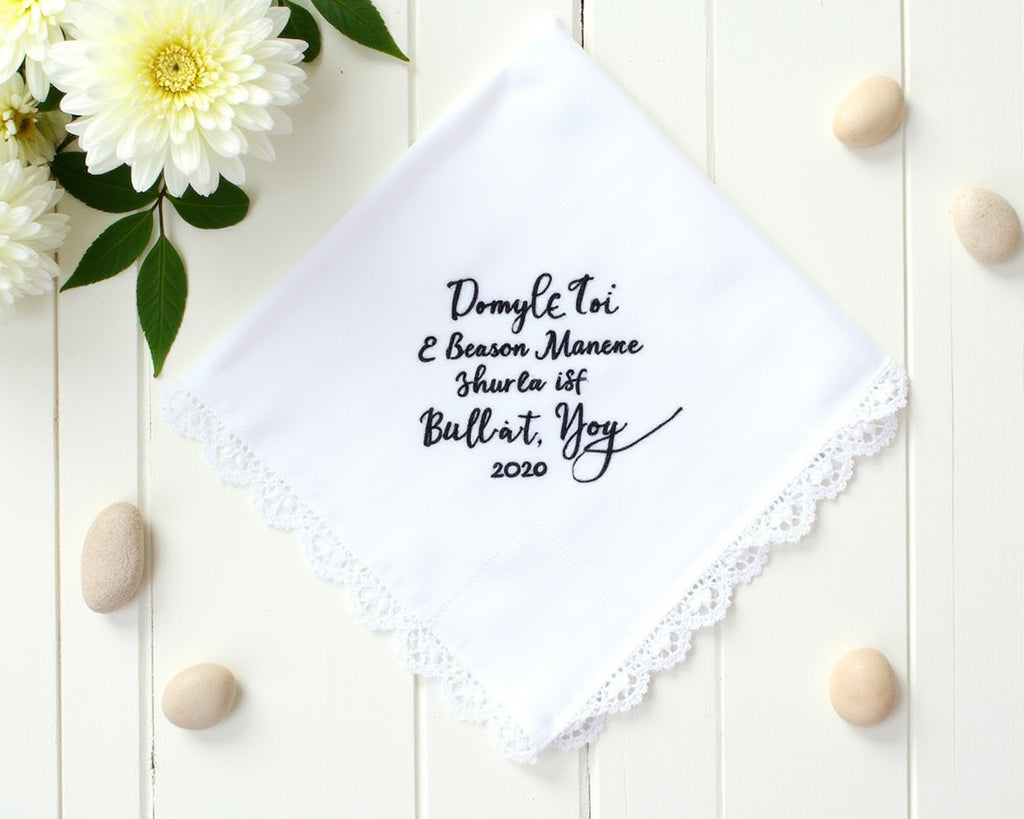 White cotton wedding handkerchief with navy blue embroidery and a wide scalloped lace border framed by white spring flowers