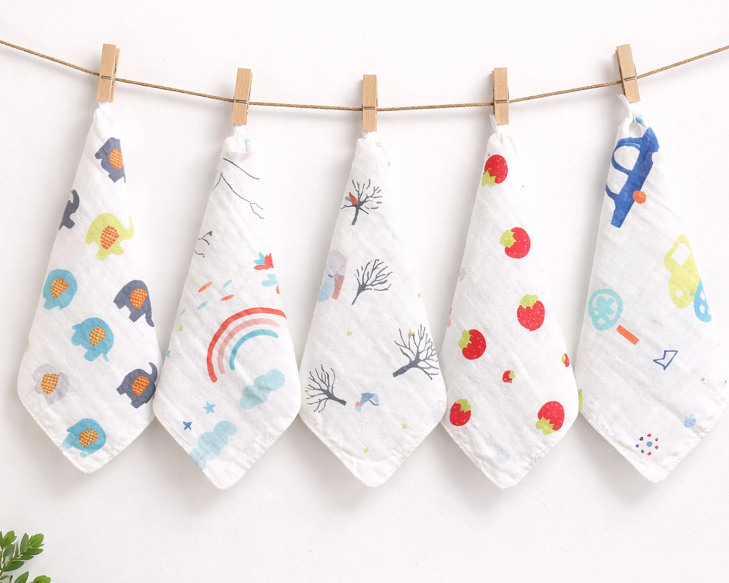 Five baby hankies with colorful prints hanging on a line against a white background