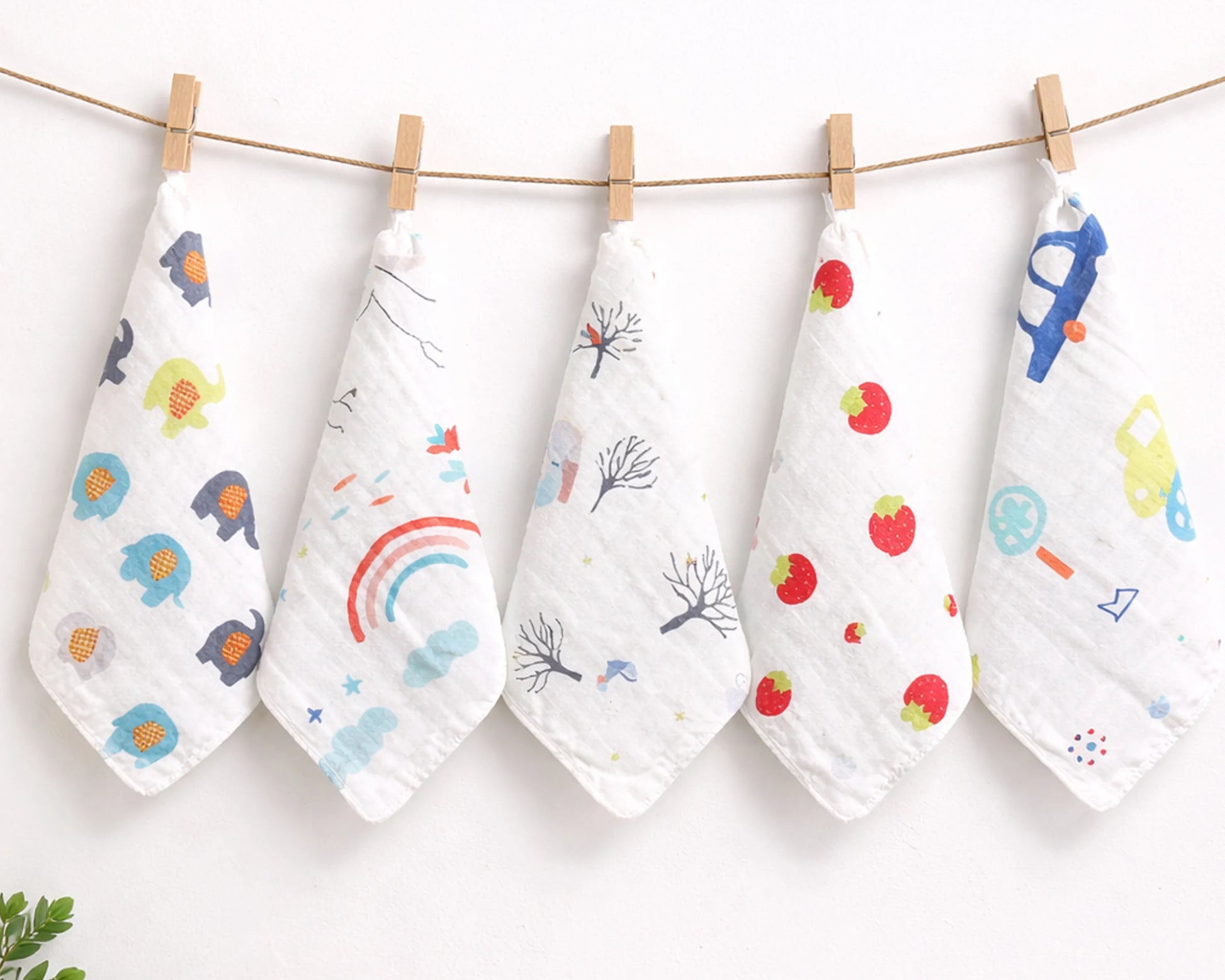 Five baby hankies with colorful prints hanging on a line against a white background