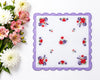 Floral-patterned handkerchief with a purple border on a white background, accompanied by a bouquet of flowers.