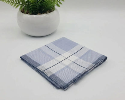 Folded blue and white checkered towel on a light gray surface with a potted plant in the background.