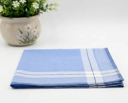 Folded blue and white checkered towel on a white surface with a potted plant in the background.