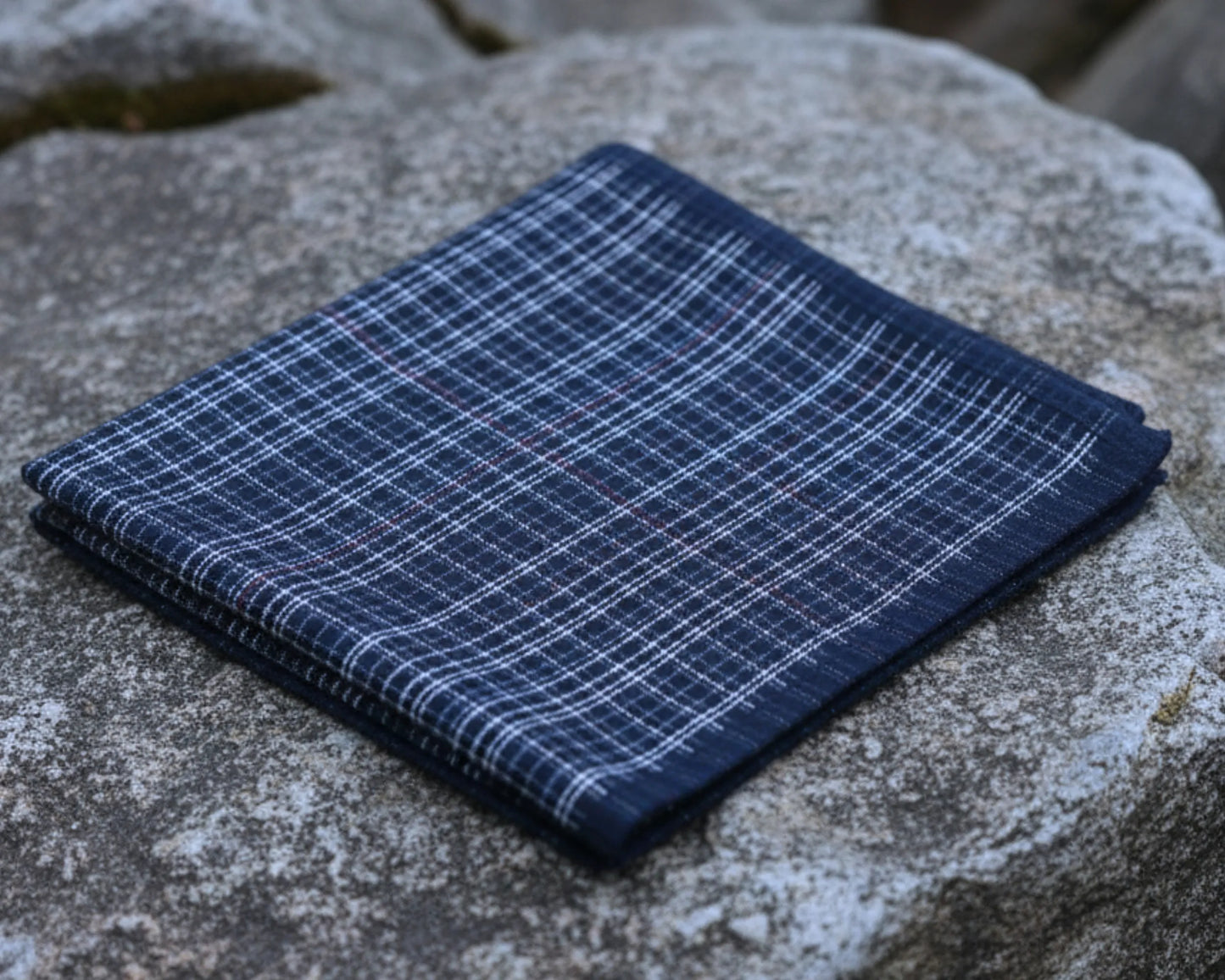 Folded blue plaid fabric on a stone surface