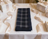 Folded navy plaid hanky on a white tablecloth with gift boxes in the background