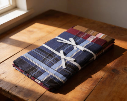 Folded plaid fabric tied with a white ribbon on a wooden surface
