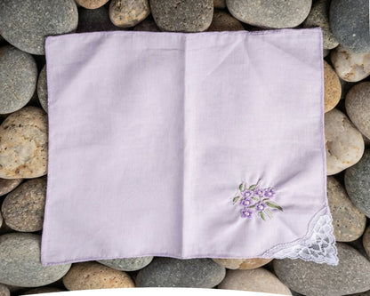 Folded purple handkerchief with floral embroidery on pebbles