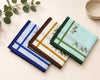 Four folded fabric hanky with different patterns on a light surface.